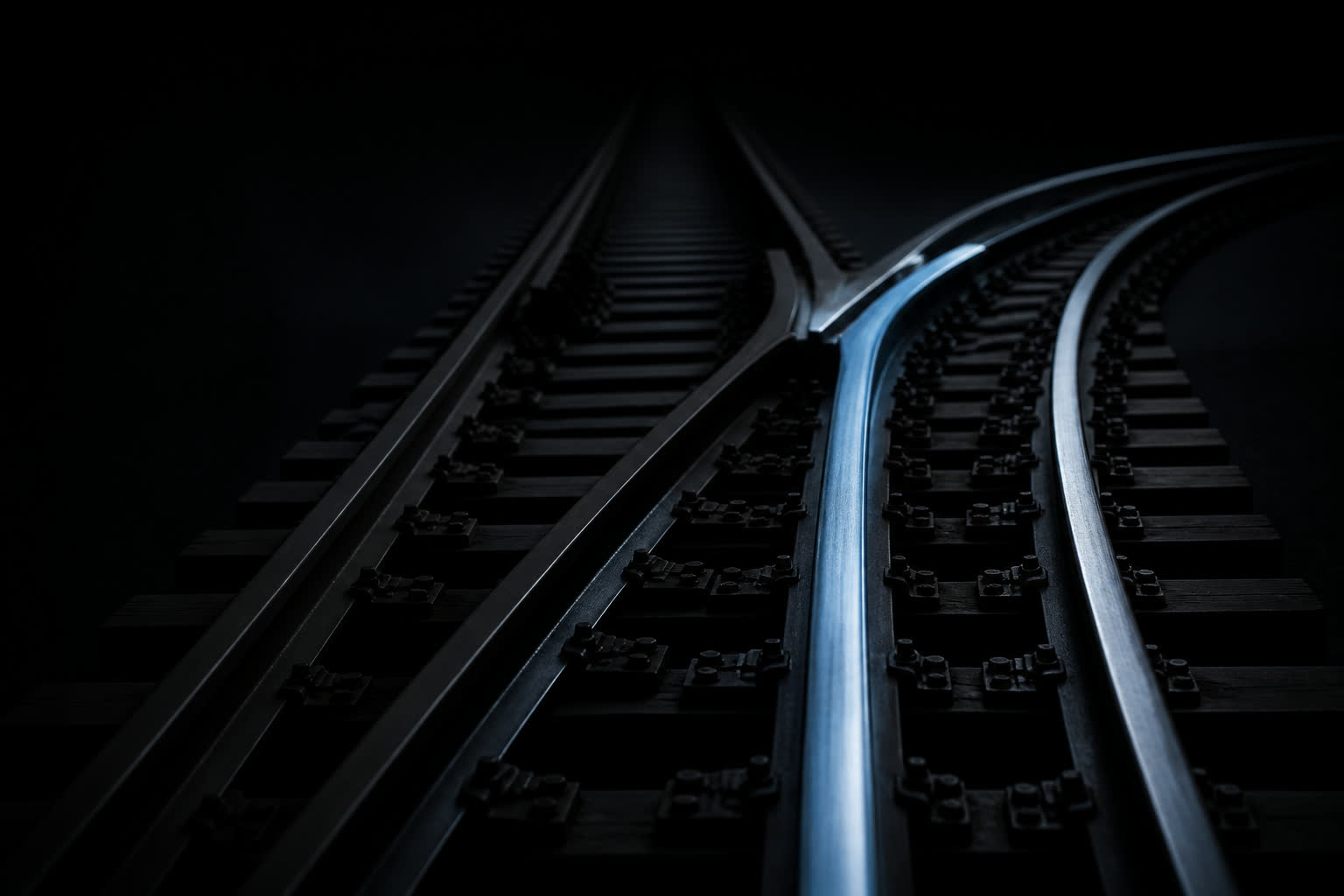 A dark rail switch with one track lit blue and the other in shadow