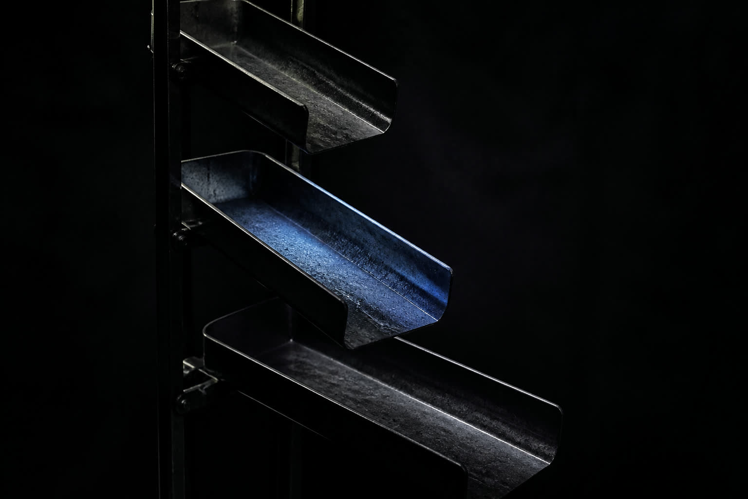 Cascading dark metal trays like a data pipeline