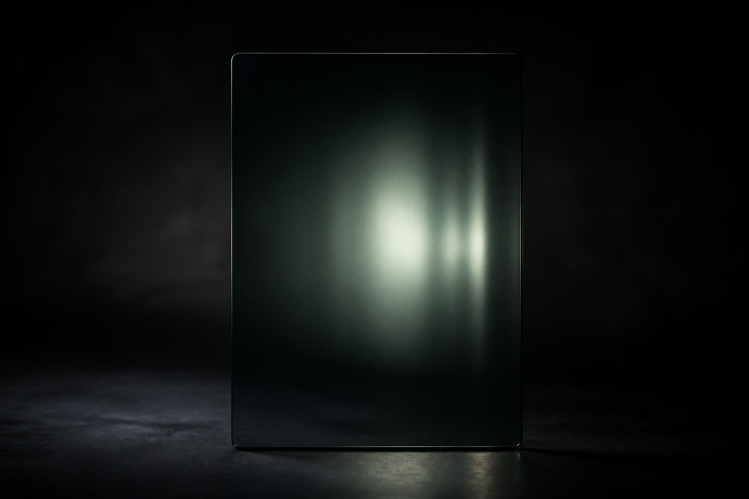 A dark glass pane with a faint volumetric light field behind it, studio still life